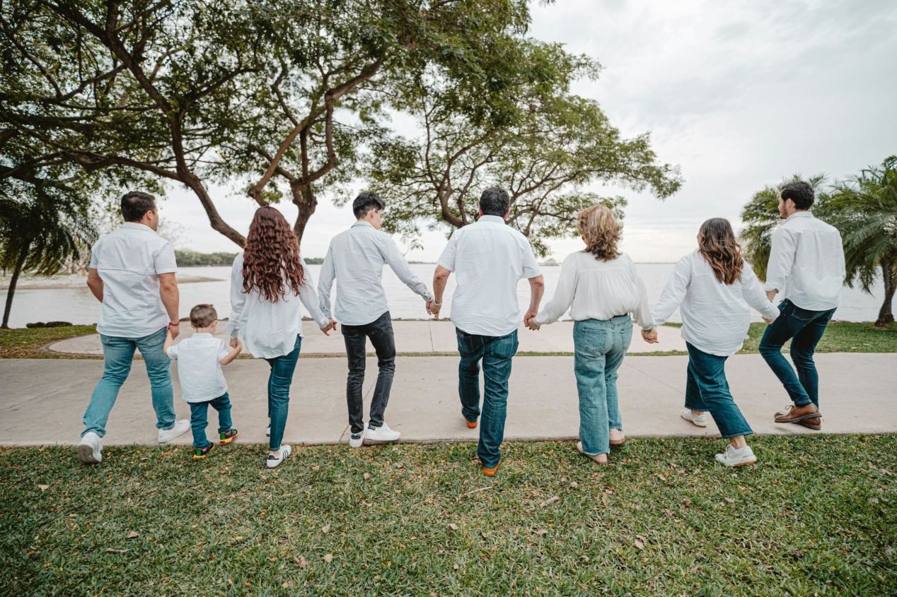 A family walks toward the lake, all wearing white tops and blue jeans
